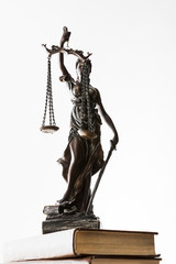 Obraz premium bronze figurine with scales of justice on brown books isolated on white
