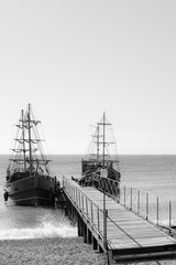 Two wooden sailing ships at the wooden pier.