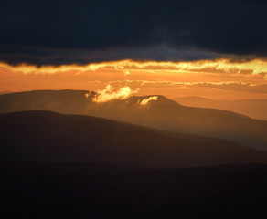 A small wisp of golden cloud emerges from the great dark cloud