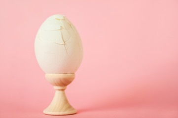 A cracked egg on a pink background close-up and copy space. One egg, easter concept, smash