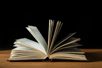 open book with white pages on wooden table isolated on black
