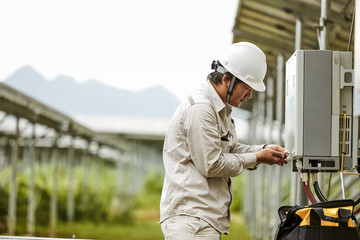 Asian engineer opening electric box in solar photovoltaic district