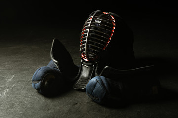 Kendo gloves and traditional helmet on dark surface