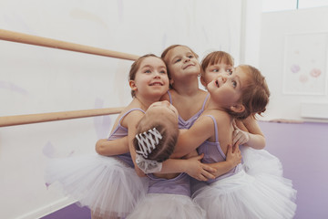 Adorable little girls hugging each other, enjoying dancing at ballet school. Cute little ballerinas embracing, having fun after ballet class, copy space. Diversity, support, togetherness concept © mad_production