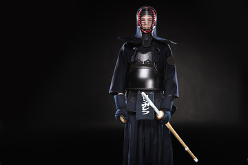 Naklejka premium Kendo fighter in armor holding bamboo sword on black