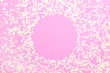 Frame of paper round confetti with clear circle in the middle on pastel pink background top view Flat lay. Festive holiday background, concept of party, birthday, christmas or new year