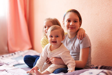 Portrait of three sisters on    bed at home. 