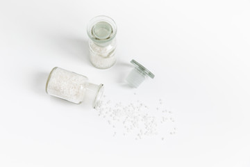 Pure Natural Coarse Sea Salt Spilling Out of A Vial On White Background