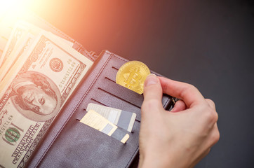 Golden bitcoin and hundred dollar bills in leather wallet. Bitcoin with dollar in purse. Profit from mining cryptocurrencies. Business, commercial. Photo with flare