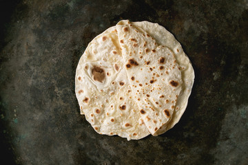 Homemade pita or chapati flatbread flapjack over dark metal background. Flat lay, space