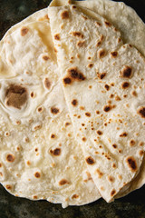 Homemade pita or chapati flatbread flapjack over dark metal background. Flat lay, close up