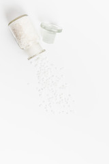 Pure Natural Coarse Sea Salt Spilling Out of A Vial On White Background