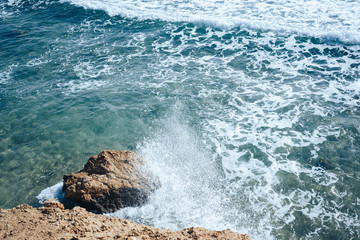 The rocky shore of the sea, in waves beating against the stone.