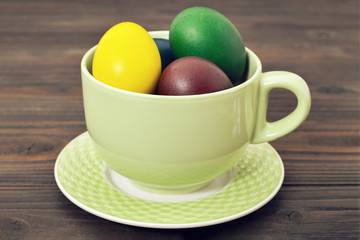 Easter eggs in the cup on wooden background