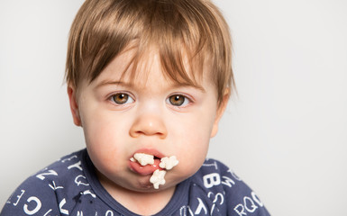 A Little boy with lot of cereal food on mouth