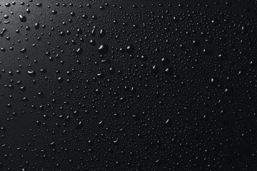 Shiny water drops on black surface, background