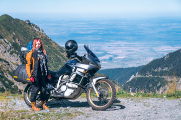 Fototapeta na wymiar Young girl with adventure motorcycle. woman rider. Top of the mountain road. Motorbike vacation. Travel and active lifestyle Transfagarasan Romaia