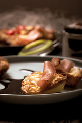 Few puff pastry cups filled by cheese and ham on blue plate with dark sauce