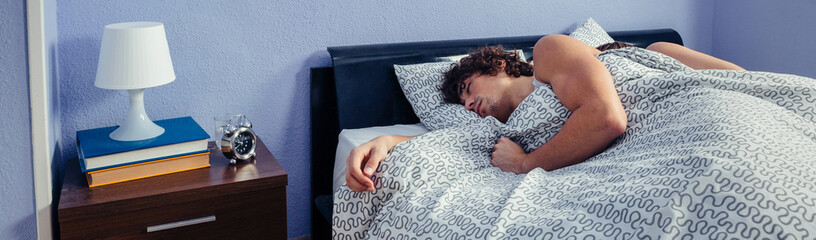 Young man sleeping with his wife on their backs in bed