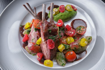 Rack of lamb with vegetables on a white plate