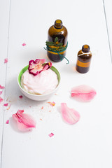 cosmetic cream, tincture, essential oil bottles, with pink flower petals, white wood table