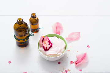 cosmetic cream, tincture, essential oil bottles, with pink flower petals, white wood table