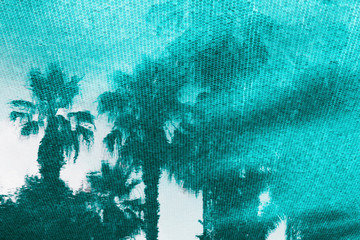 Small elements turquoise mosaic on the bottom of the pool pattern. Reflections of palm trees on the water surface. Travel background. Close up.