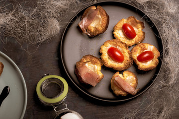 Several puff pastry cups stuffed by cheese with tomatoes and ham