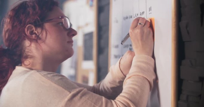 Creative woman is sticking notes on whiteboard