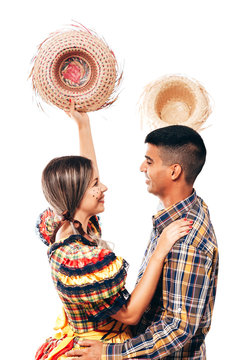 Brazilian couple wearing traditional clothes for Festa Junina - June festival - dancing isolated on white background