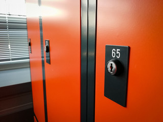Closeup of locker room situated in work place. Orange lockers, storage for workers.