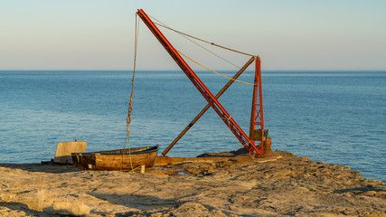 A fishing boat and a crane near Portland Bill Lighthouse, Jurassic Coast, Dorset, UK