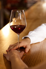 Connections made. Cropped closeup of a man touching the hand of a woman holding a glass of wine on a bar counter 