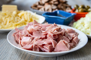 Ingredients for pizza: sliced mushrooms, ham, onion, ketchup, cheese and olives in a bowls on kitchen table