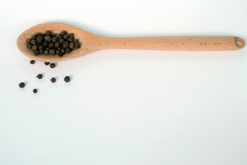 Black pepper in wooden spoon.