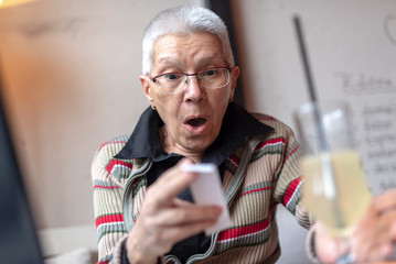 Senior older woman in a cafe shocked by the price she has to pay for her order