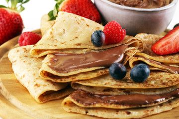 Delicious Tasty Homemade crepes with chocolate or pancakes with raspberries and blueberries on rustic wood