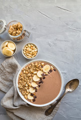 Chocolate smoothie bowl with bananas, granola and peanuts