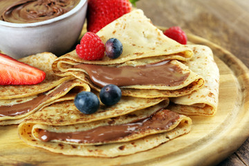 Delicious Tasty Homemade crepes with chocolate or pancakes with raspberries and blueberries on rustic wood