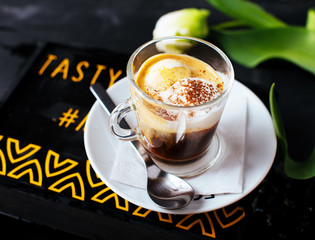 A glass cup of espresso with ice cream on top and cinnamon.