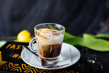 A glass cup of espresso with vanilla ice cream on top on black background.