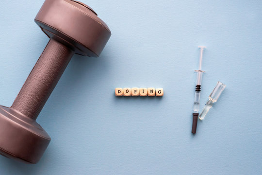 The concept of doping in sport. Inscription Doping on a blue background. Syringe with medicine, fillett and ampoule.