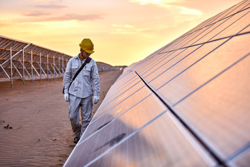 Asian engineer patrolling the desert solar photovoltaic power station in the sunset