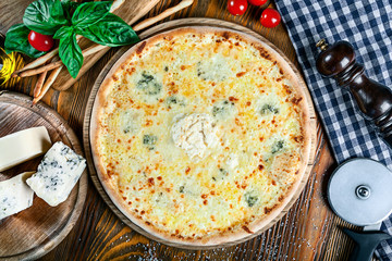 Top view on homemade italian four cheeses pizza. Pizza on rustic wooden background with tomato, cheese, basilic. Copy space. Traditional italian cuisine. Flat lay picture for recipe or menu