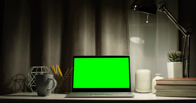 Close up of the black laptop computer with green screen on the table in the cabinet at home. At home. Chroma key.