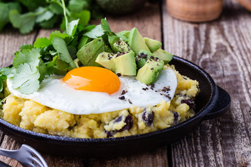 Healthy vegetarian  brunch with  grits, black beans,  avocado topped fried egg
