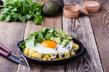 Healthy vegetarian  brunch with  grits, black beans,  avocado topped fried egg