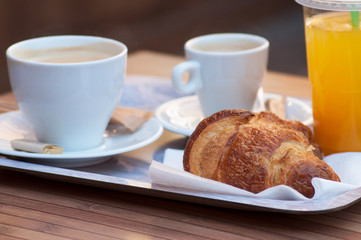 closeup of breakfast with cup of coffee, french croissant and orange juice on wooden table background