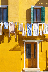 Colorful houses of Burano Island. Venice. Typical street with hanging laundry at facades of colorful houses 