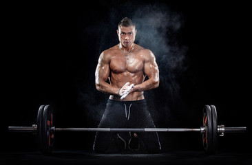 Fototapeta na wymiar Photo of strong muscular bodybuilder athletic man pumping up muscles with barbell on black background. Workout energy bodybuilding concept.